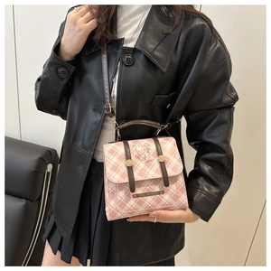 Detail of pink plaid bag with cartoon bear illustration and brown leather straps