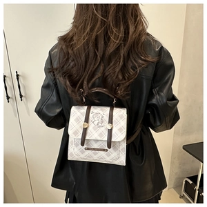 Detail view of mini plaid backpack showing bear pattern and brown straps on a model