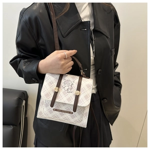 Détail du sac à bandoulière à carreaux avec imprimé ours et sangle en cuir