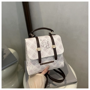 Detailed view of checkered backpack with cute dog illustration and leather straps