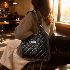 Gesteppte schwarze Puffer-Tasche mit Rautenmuster und Glanz-Finish an der Schulter getragen