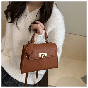 Detailopname van de karamelkleurige leren tas met gouden gesp en luxe structuur