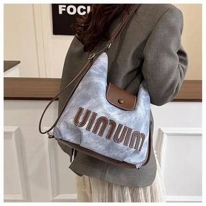 Detail of blue denim tote bag with brown leather patchwork and shoulder strap fit