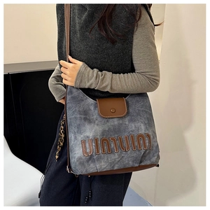 Macro view of grey canvas texture and brown leather flap with embossed letter detail