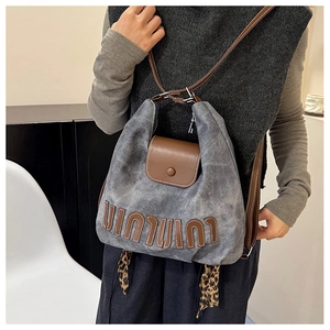 Detail eines grauen Segeltuchrucksacks mit braunem Lederbesatz und Leopardenmuster-Schal