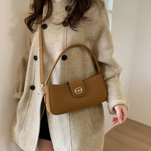 Caramel suede baguette bag with gold metal buckle shown on model in beige winter coat