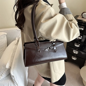 Sac baguette rétro en cuir marron foncé avec boucle argentée porté par un mannequin