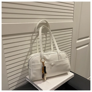 Detail of white PU leather pillow bag with stylish wooden bead charm and long strap
