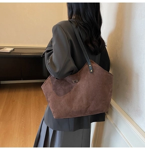Detail of coffee brown quilted faux suede tote bag with metal twist lock closure