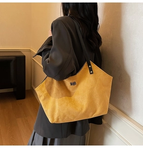Detail of yellow quilted tote bag with suede texture and metal turn-lock closure