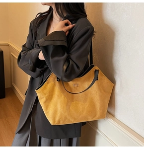 Detail of yellow quilted tote bag with black handles and golden twist lock closure
