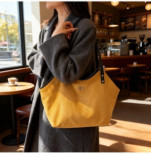 Detail of yellow quilted suede tote bag with golden lock and black shoulder strap