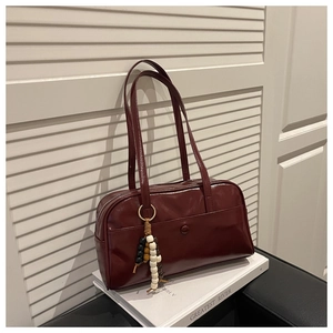 Detail view of a vintage dark red bowling bag with beaded charm and double handles