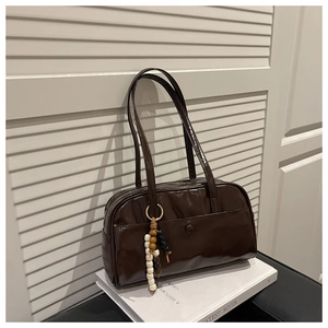 Detail of dark brown glossy leather boston bag with beaded charm and front pocket