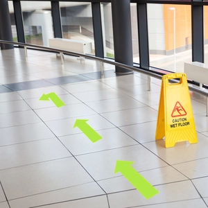 Neon green floor arrow stickers for indoor directional guidance in public walkways