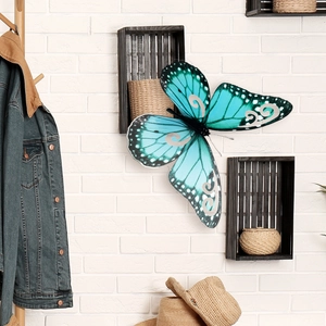 Mariposa 3D grande turquesa decorativa con patrones plateados en pared de ladrillo