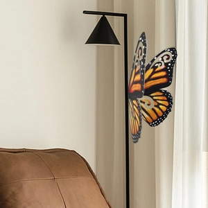 Detalle de un adhesivo decorativo de mariposa 3D naranja y negro en la pared del salón