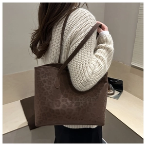 Side view of a large leopard print tote bag with thin leather straps on a model
