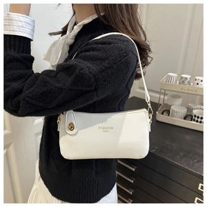 Detail of white lychee leather texture with golden FASHION BAG text and rotary lock