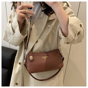 Detail shot of brown lychee leather crescent bag with golden Fashion Bag logo on a model