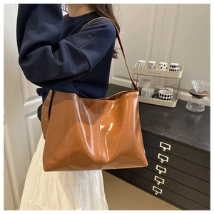 Detail of caramel glossy patent leather tote bag with vertical stitching and metal eyelets