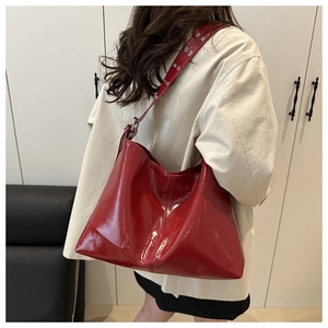 Detail of red glossy tote bag with wide eyelet shoulder strap and smooth patent finish