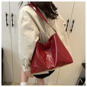 Detail of red glossy patent leather tote bag with wide strap for casual wear