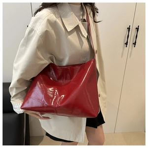 Detail of red patent leather tote bag showing glossy texture and slim shoulder straps