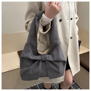 Detail der grauen Cord-Handtasche mit großer Schleife und Rippstruktur an der Schultertasche