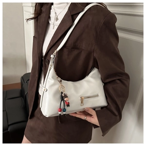 Detail of white oil wax leather hobo bag with zip pocket and cute pendant on a model