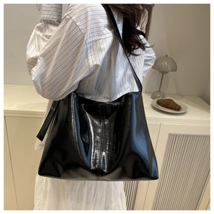 Detailed view of black patent leather tote bag styled on model for daily commute