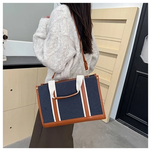 Détail du sac cabas en toile marine avec bordure en cuir porté avec un pull en maille blanc