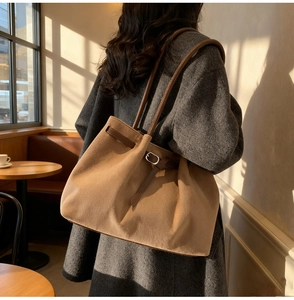 Detail of camel wool tote bag with brown leather straps in a cozy cafe setting