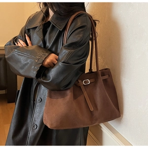 Close-up of brown suede tote bag with metal buckle detail and shoulder straps