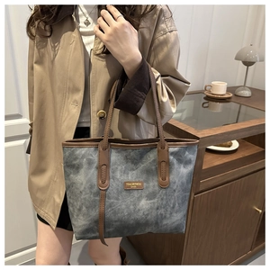 Detail of grey vintage tote bag with brown leather handles and brand leather label
