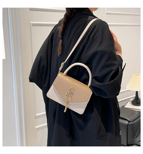 Sac bandoulière tendance en texture tissée avec logo doré porté par un mannequin