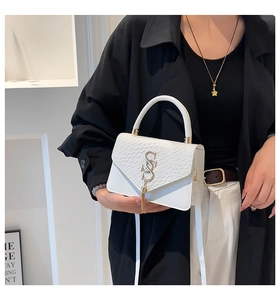 Détail d'un sac à main en cuir blanc avec logo S doré en métal et texture raffinée