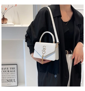 Détail du sac carré blanc avec ferrures dorées en S et de élégantes longues franges fines