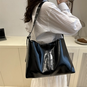 Glossy black patent leather tote bag with eyelet straps for casual everyday wear