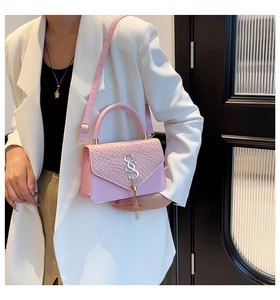 Detail of light pink crossbody bag with woven texture flap and silver tassel charm