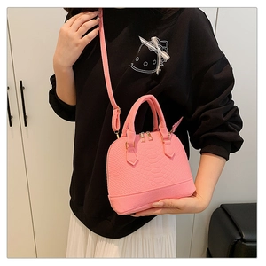 Detail view of pink crocodile embossed shell bag with gold hardware and detachable strap