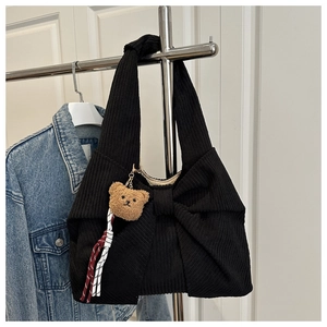 Detail of corduroy shoulder bag with large bow design and brown plush bear charm