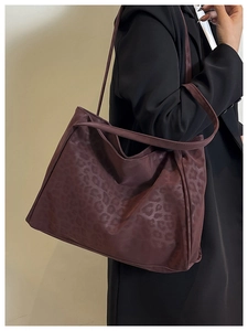 Detail view of burgundy leopard print tote bag with soft texture worn with black coat
