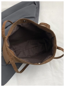 Overhead view of brown faux leather tote bag with silver magnetic snap and fabric lining