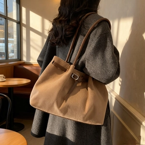 Grand sac cabas en daim camel avec bandoulières marron, porté dans un décor de café