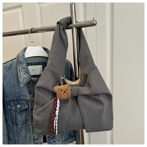 Detail of grey corduroy handbag with large bow and cute plush bear charm accessory