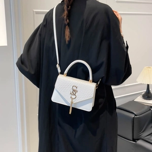Sac à main blanc effet serpent avec fermoir doré porté par un mannequin en intérieur