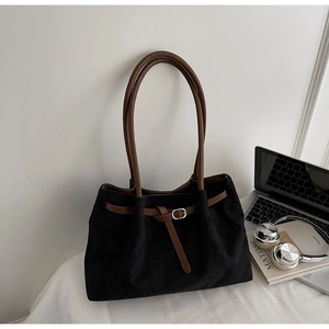 Detail of black faux suede tote bag with brown leather straps and metal buckle detail