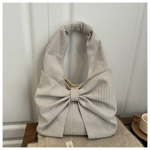 Détail macro du sac à main en velours côtelé beige avec grand nœud et poignée froncée