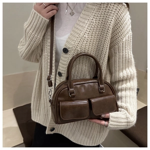 Detail of vintage brown bowler bag with two front flap pockets and dual handles